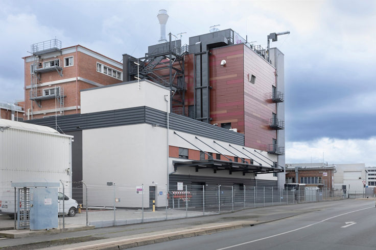 evonik manufacturing plant, red brick building with silver pipes with road in front and blue sky